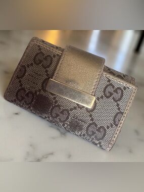 Gucci GG canvas key case with a gold-tone bar and snap closure